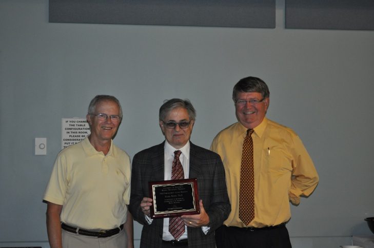 Three men standing next to each other holding a plaque.