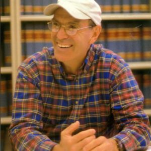 A man in glasses and a hat sitting at a table.