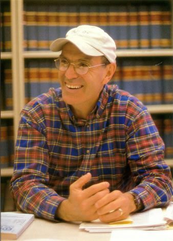 A man in glasses and a hat sitting at a table.